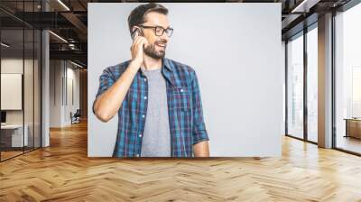 Oh, great news! Smiling young casual man talking on the phone on the grey background. Isolated. Wall mural