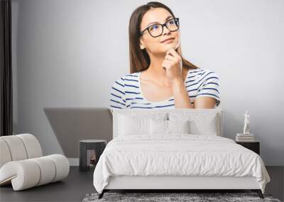 Portrait of happy young beautiful thinking woman standing with laptop isolated on white background. Space for text. Wall mural