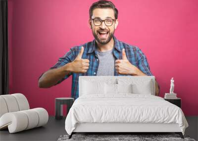 Portrait of young man in glasses showing thumbs up isolated over pink background Wall mural