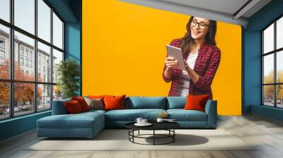 Portrait with copy space empty place of pretty charming confident smiling woman in casual having tablet in hands isolated on yellow background. Wall mural