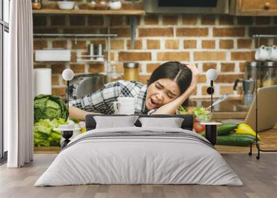 Tired young beautiful girl sleeping on the table of the kitchen at breakfast. Stress. Wall mural