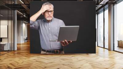 Too much work to do. Tired angry senior aged man with laptop computer isolated against black background. Wall mural