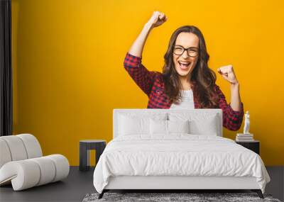 Winning success woman happy ecstatic celebrating being a winner. Dynamic energetic image of multiracial Caucasian Asian female model isolated on yellow background waist up. Wall mural