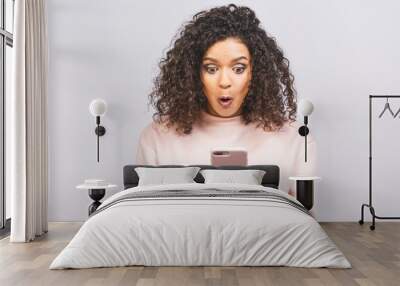 Wow, amazing! Portrait of african american surprised attractive cheerful optimistic wavy-haired girl using new device gadget isolated over white background. Wall mural