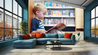 Preschool child reading a book at the library Wall mural