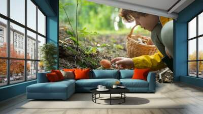 Cute little boy on a walk in the forest found an edible mushroom. The student gets to know the nature around and studies it. Wall mural