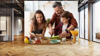 Mother, father, son chopping vegetables on kitchen Wall mural