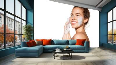 Portrait of young pretty girl with healthy skin on white background. Woman smiling and applying cosmetic foam on face.  Beauty skincare concept. Wall mural