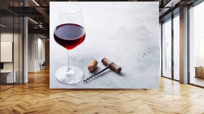 Elegant glass of red wine with cork and opener on stone kitchen table background. Wall mural