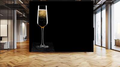 Elegant glass of yellow champagne with bubbles on black marble board on black background. Space for text Wall mural