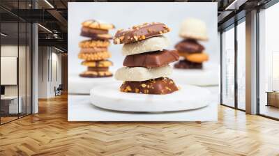 Luxury belgian chocolate and biscuit cookies selection on marble coasters and white kitchen table background. Wall mural