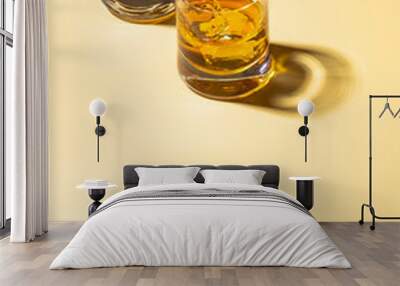 Two whiskey glasses with ice cubes on golden background. Wall mural