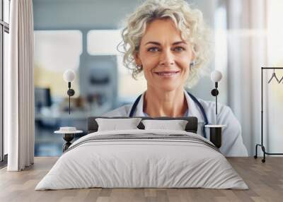 Confident doctor woman in a white medical coat with stethoscope around her neck looking at the camera. Middle aged senior female professional, mature lady. Wall mural