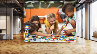 31.07.2017 - Kyiv, Ukraine. Group of funny kids playing with block toys indoor. Cute kids playing together indoor. Preschool early education. Wall mural