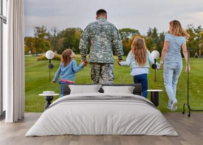 Back view soldier's family walking. Soldier at vacation. Four family members walking together holding hands. Wall mural