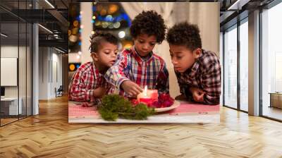 Black boys light Christmas candles. Wall mural