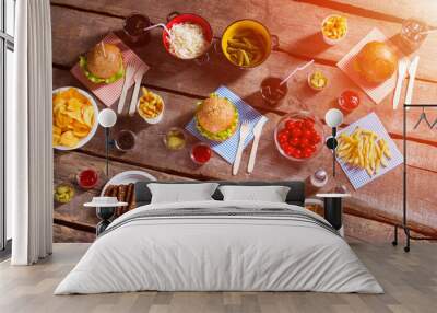 Burgers and pickles with tomatoes. Beverages and food on table. Cooked food with cool drinks. Weekend meal for guests. Wall mural