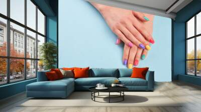 Hands with beautiful manicured nails. Girl hands with beautiful summer manicure on blue background in studio. Manicured hands and copy space. Wall mural