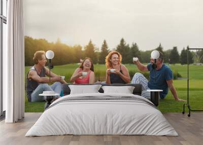 Happy people laughing. Tea party conversation outdoor in the summer park. Wall mural