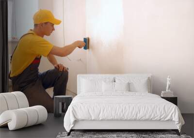 Man applying wallpaper glue using a brush. Construction worker making renovation in a living room. Wall mural