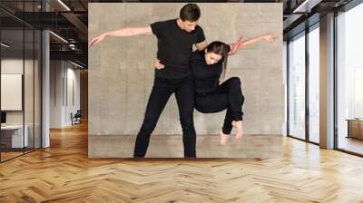 Partnering dance on grey background. Attractive young couple of dancers dancing at pole in a fitness studio. Wall mural