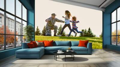 Reunion of soldier and daughters outdoor on the lawn. Daddy came back from us army. Wall mural