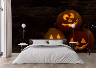 Three pumpkin Jack-O-Lantern with happy faces. Carved Halloween pumpkins with burning candles inside. Halloween festive decorations. Wall mural