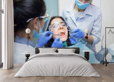 Two dental doctors and patient. Procedure at the dentist office. Wall mural