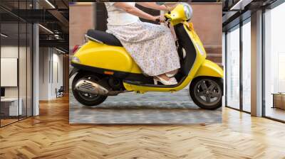 Woman riding on a scooter. Yellow scooter on the road. Decrease speed to save fuel. Long way home. Wall mural