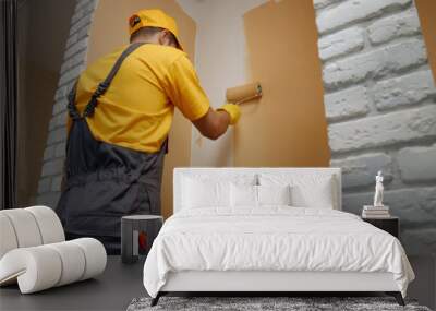 Worker painting wall with paint roller. Builder paints the wall in brown color. Building, renovation and people concept. Wall mural