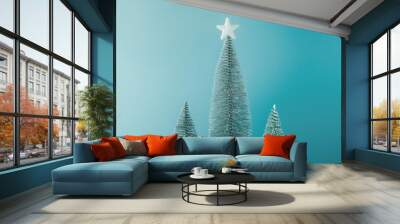 Three minimal christmas tree decors with one that has a white star on it against a blue background
 Wall mural