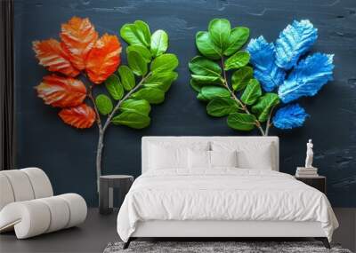 Two Painted Branches With Green, Orange, and Blue Leaves on a Dark Wooden Surface Wall mural