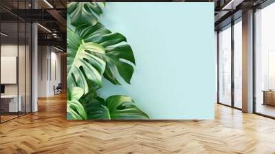 Creative arrangement of tropical monstera leaves against blue abstract wall background Wall mural