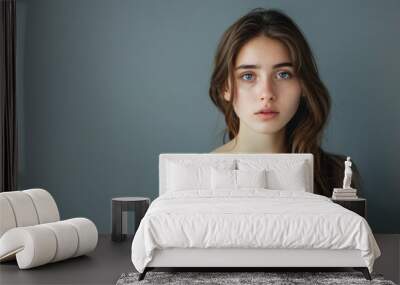 Young woman expressing curiosity standing against a solid studio background Wall mural