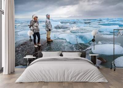 Extremely beautiful tourists stand on the massive icebergs in lake Jokulsarlon in Iceland in winter Wall mural