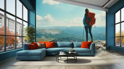 A female hiker stands on a mountaintop, looking out over a vast and beautiful landscape. Wall mural