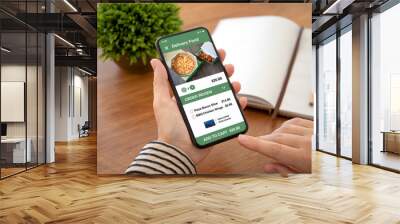 female hands holding phone with app delivery food on screen Wall mural