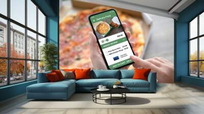 female hands holding phone with delivery food app pizza box Wall mural