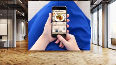 woman holding phone with app delivery food on screen Wall mural