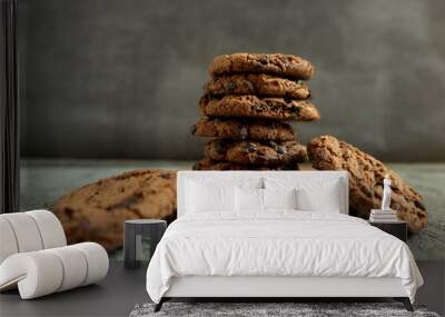 A pile of chocolate cookies with chocolate chips on top, on a textured gray table Wall mural