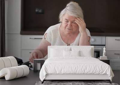  A woman has a headache. Grandma is sitting at the table in the kitchen Wall mural