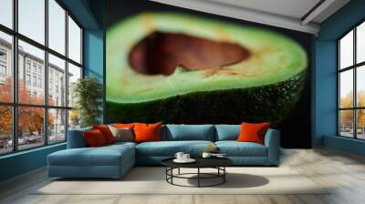 green avocado on black wooden background close-up Wall mural