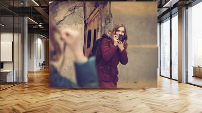 Young girl photographing female model on winter street, image with warm vintage toning Wall mural