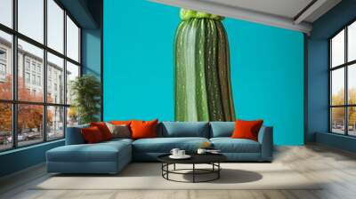 Single zucchini standing upright with a chef's hat perched atop, set against a vibrant turquoise backdrop. The image evokes a playful and creative approach to food and culinary arts Wall mural