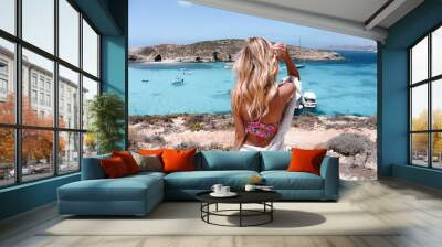 young beautiful girl travel blogger standing on top of rock looking at bright blue sea in lagoon in Malta Wall mural