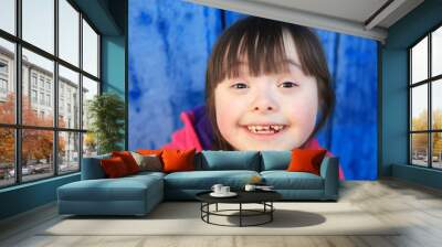 Young girl smiling on background of the blue wall. Wall mural