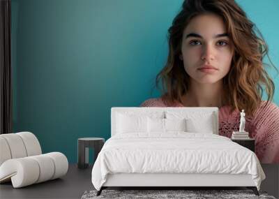 A young woman with an angry expression, wearing a pink sweater against a blue background. Wall mural