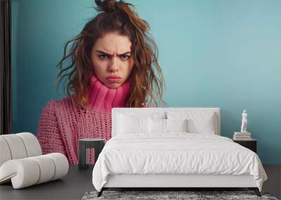 A young woman with an angry expression, wearing a pink sweater against a blue background. Wall mural