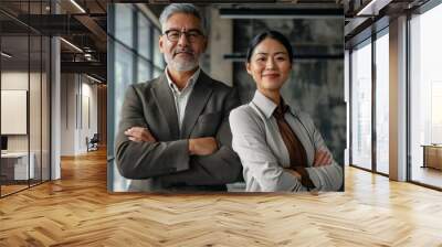 Happy confident professional mature Latin business man and Asian business woman corporate leaders managers standing in office, two diverse executives team posing arms crossed, Generative AI Wall mural