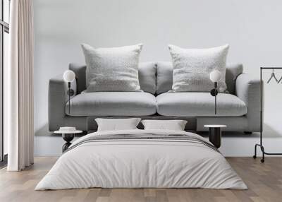 A comfortable light grey sofa with two pillows, positioned against a white background.
 Wall mural